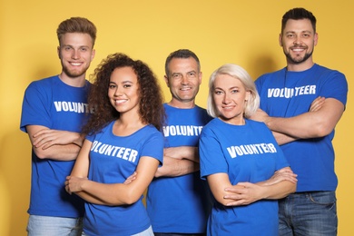 Team of volunteers in uniform on yellow background