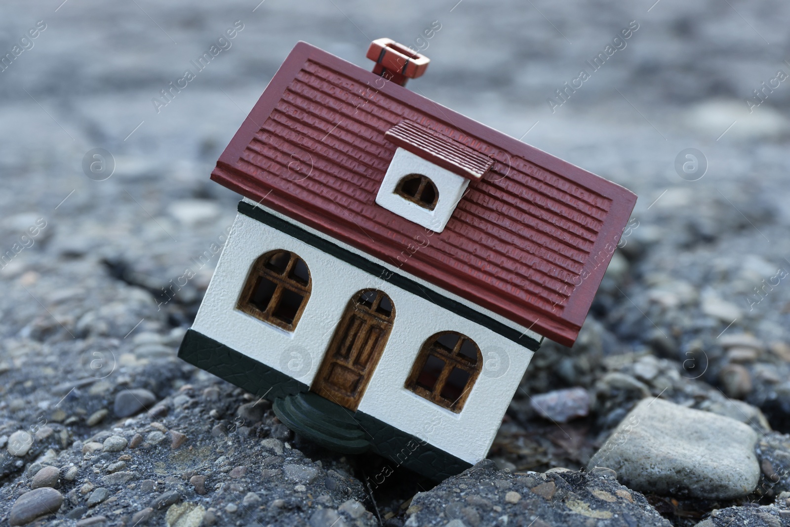 Photo of House model in cracked asphalt. Earthquake disaster