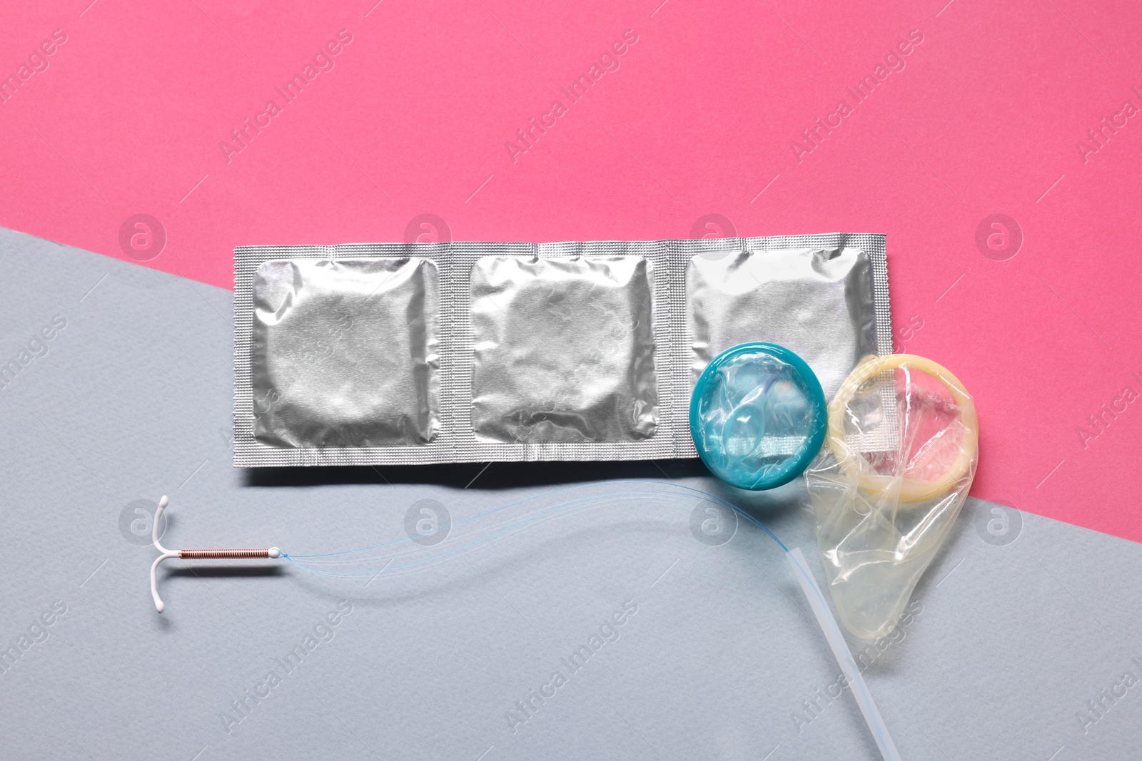 Photo of Condoms and intrauterine device on color background, flat lay. Choosing birth control method