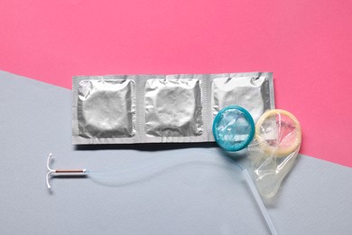 Photo of Condoms and intrauterine device on color background, flat lay. Choosing birth control method