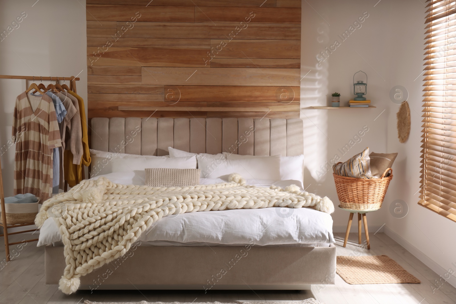 Photo of Bed with white knitted plaid in room. Interior design