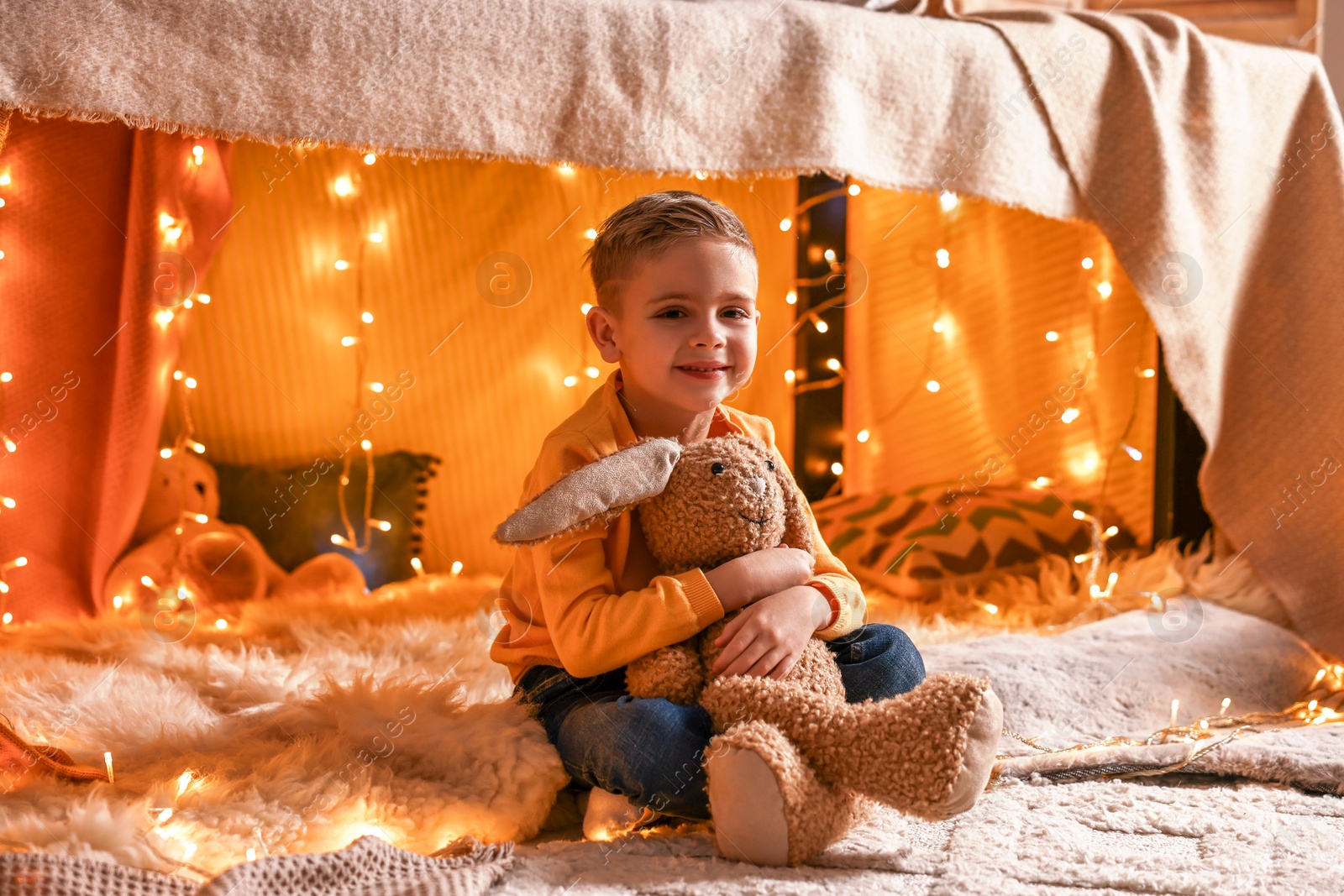 Photo of Boy playing with toy bunny in play tent at home