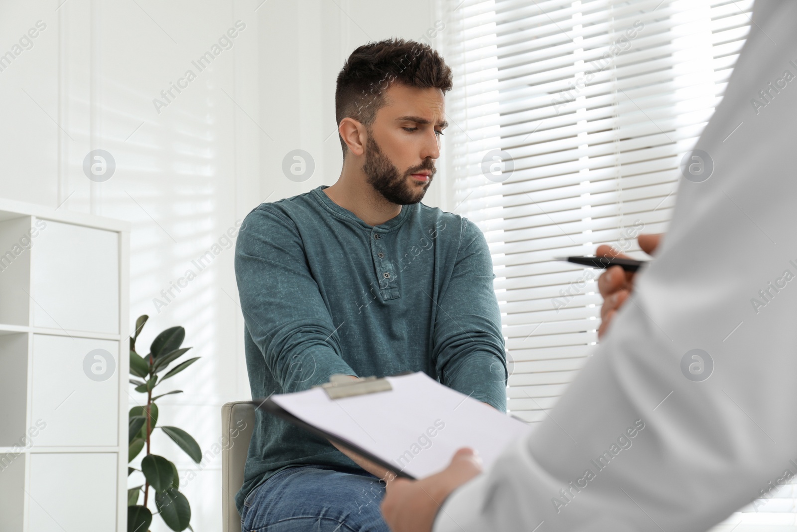 Photo of Psychotherapist working with drug addicted man indoors