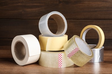 Photo of Many different rolls of adhesive tape on wooden table