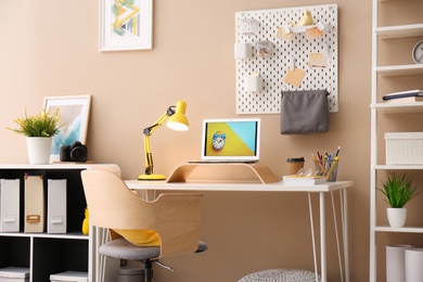 Photo of Modern laptop on desk in room. Home workplace