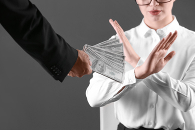 Woman refuses to take bribe money on dark background, closeup