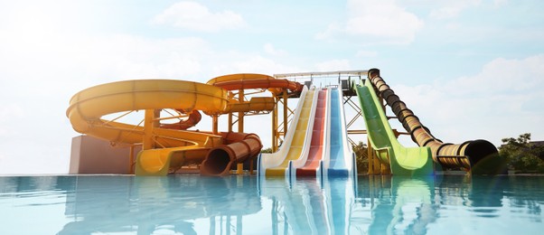 Beautiful view of water park with colorful slides and swimming pool on sunny day. Banner design