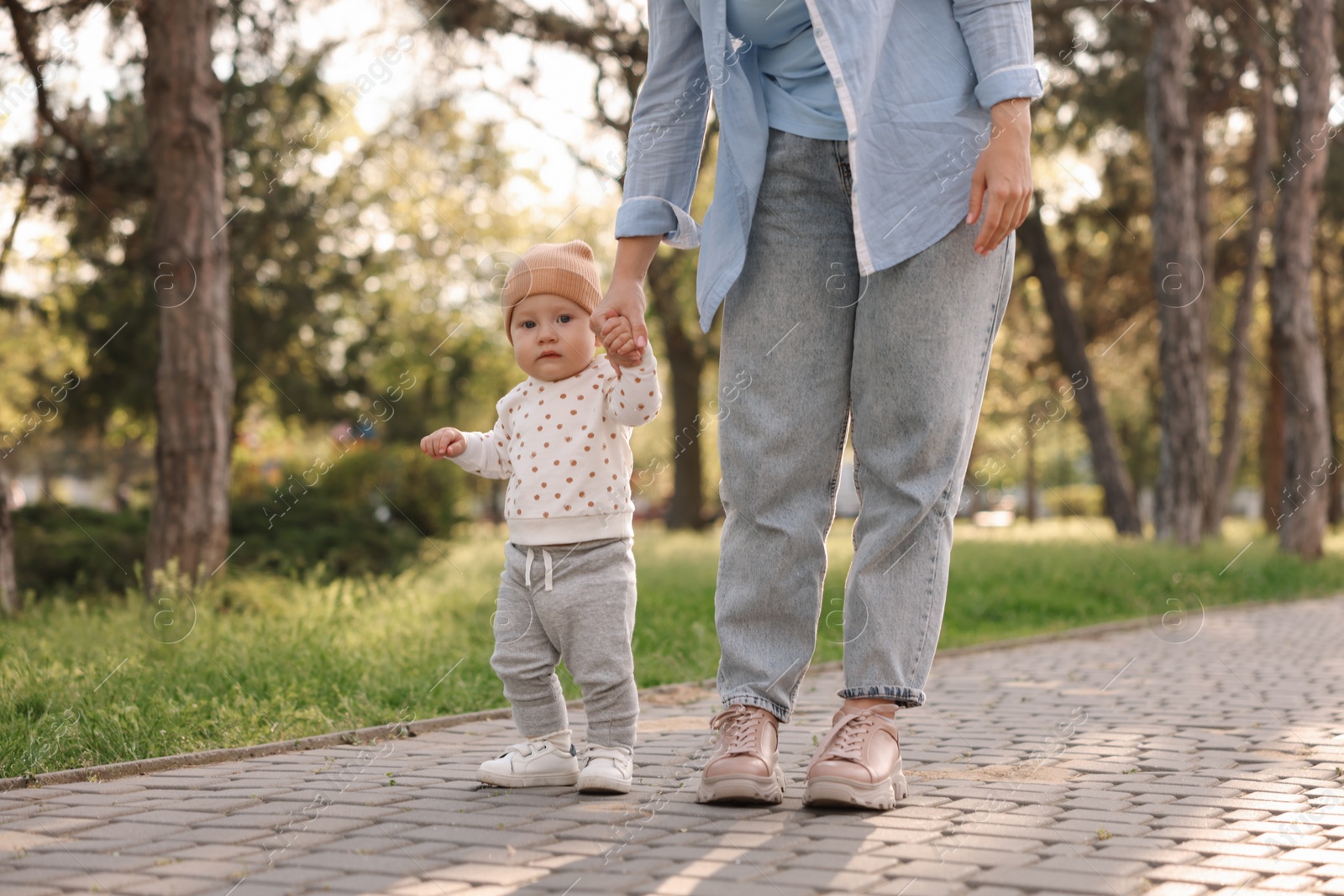 Photo of Mother supporting her baby while he learning to walk outdoors, closeup