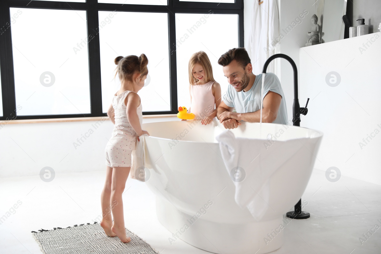 Photo of Young father with little daughters in bathroom