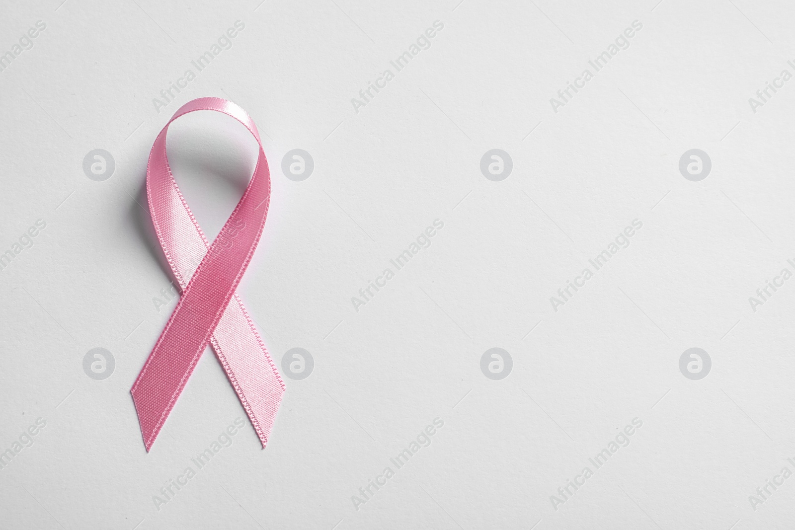 Photo of Pink ribbon on white background, top view. Cancer awareness