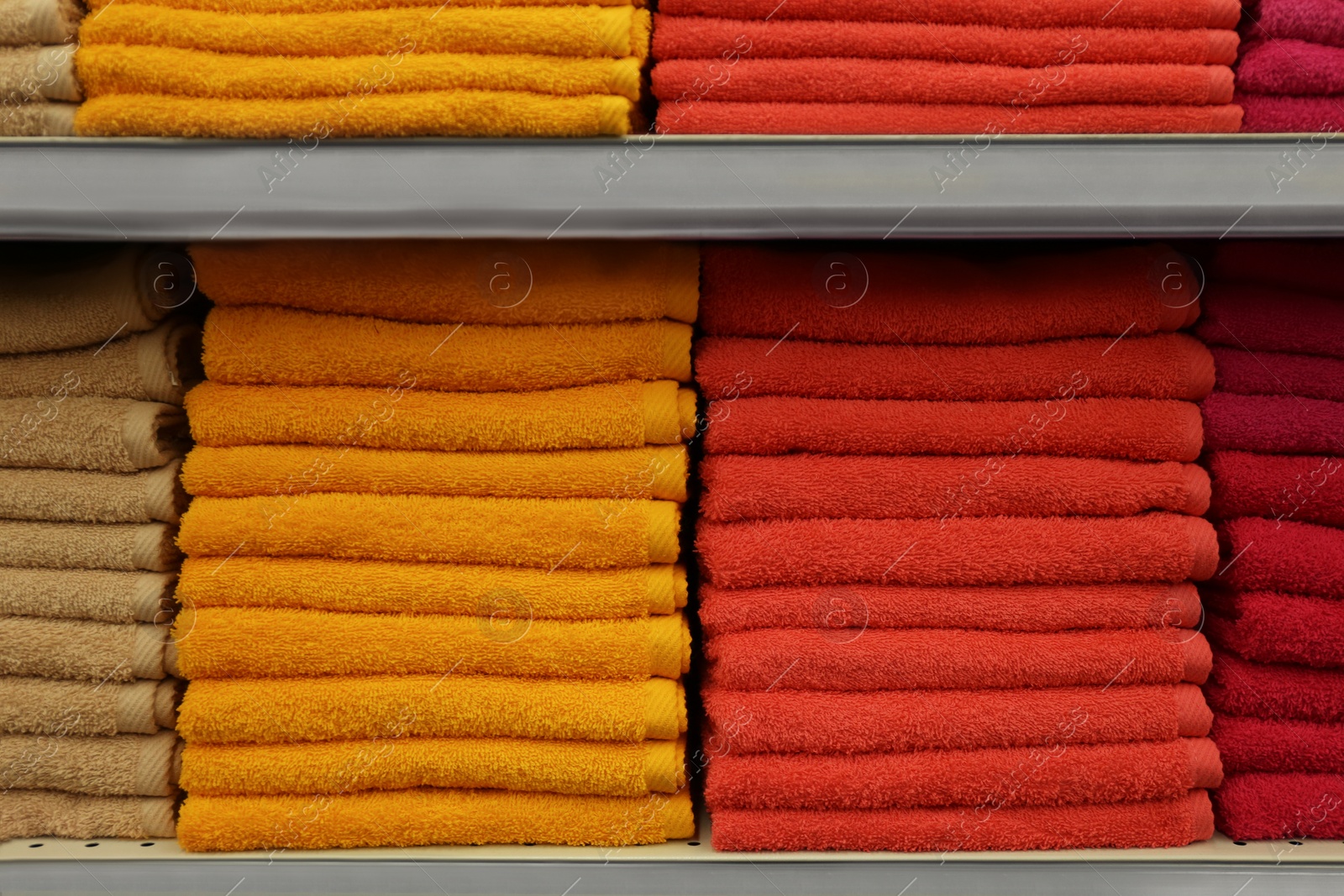 Photo of Stacks of colourful towels on store shelves