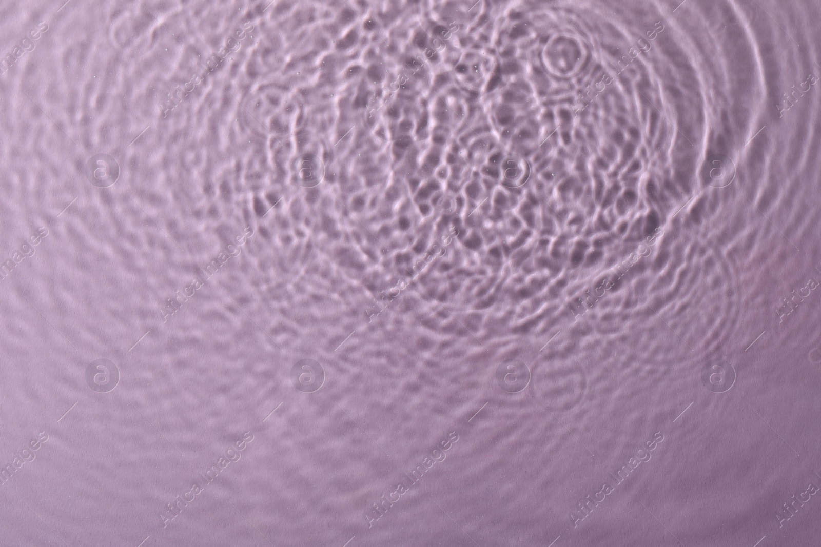 Photo of Clear water with rippled surface on pink background, top view