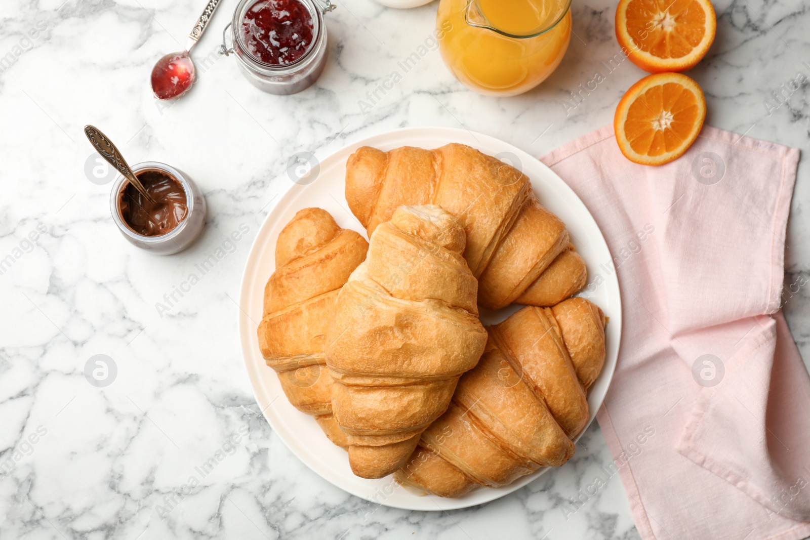 Photo of Tasty croissants with chocolate sauce and jam served for breakfast on table, top view