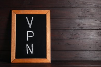 Photo of Chalkboard with acronym VPN on wooden table, space for text