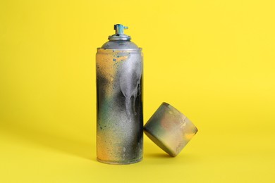 Photo of One spray paint can with cap on yellow background