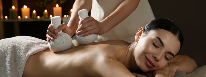 Image of Young woman receiving herbal bag massage in spa salon. Banner design