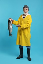 Photo of Fisherman with caught fish on light blue background