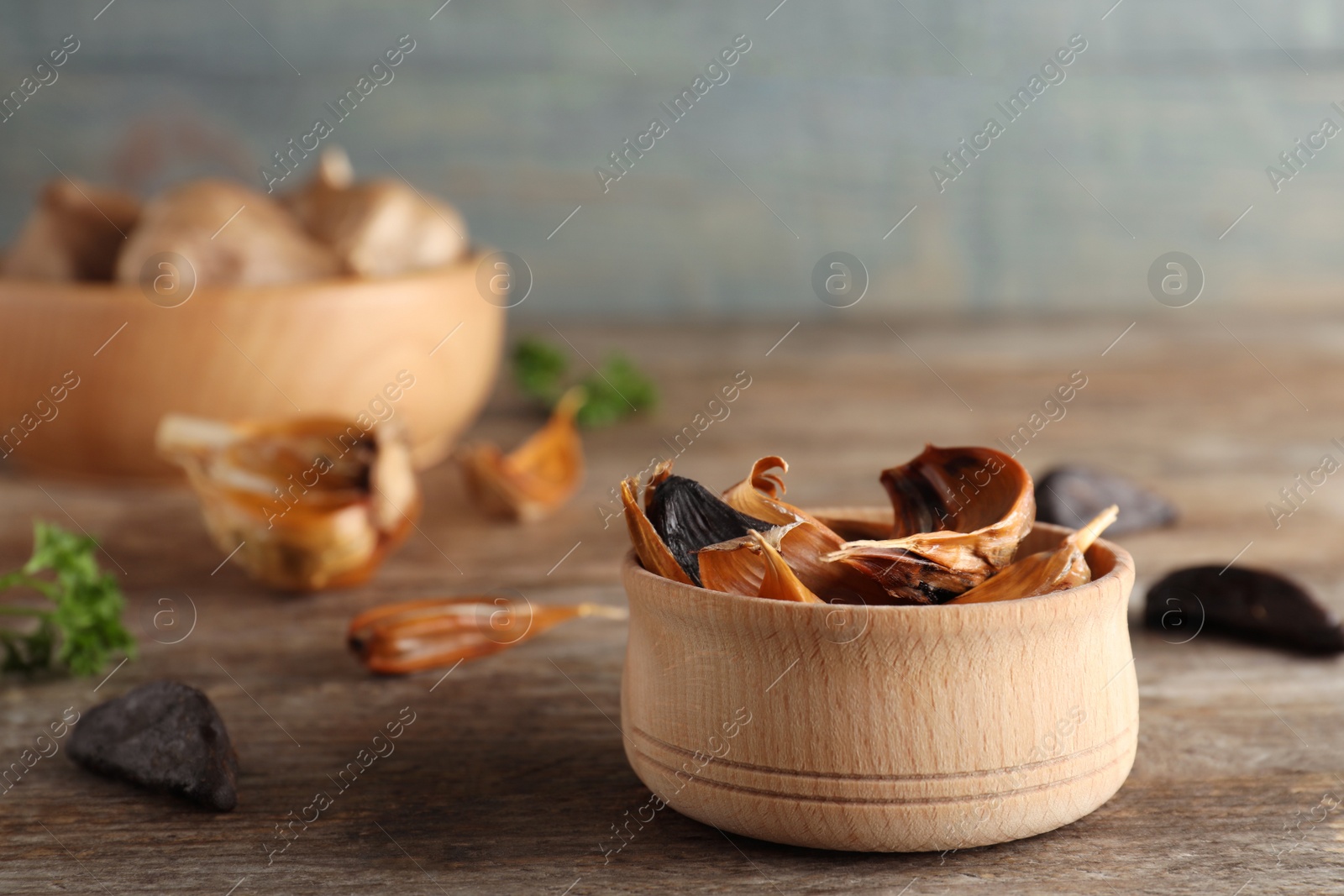 Photo of Bowl of black garlic on wooden table. Space for text