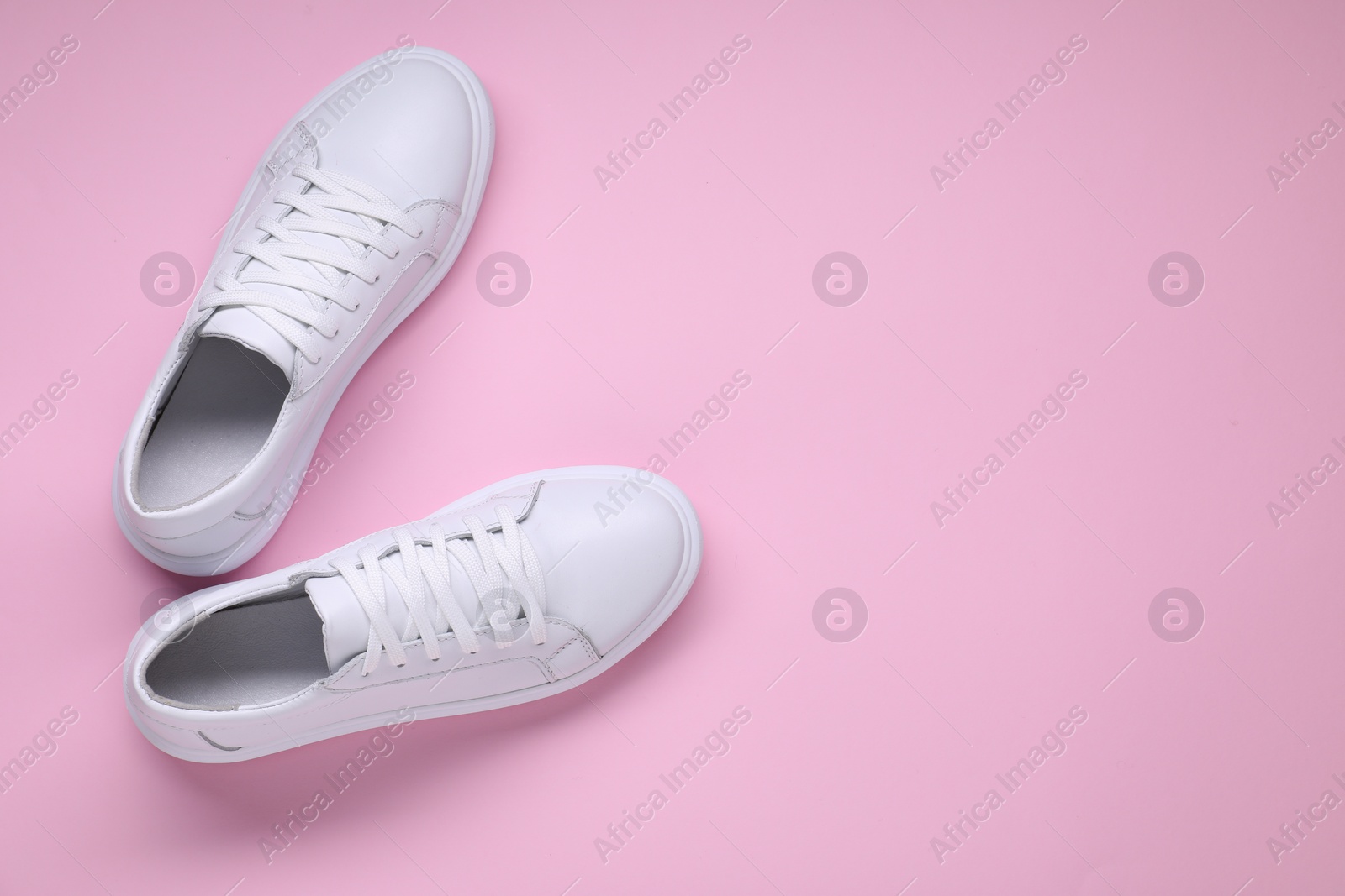 Photo of Pair of stylish white sneakers on pink background, top view. Space for text