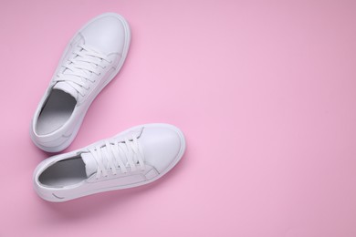 Photo of Pair of stylish white sneakers on pink background, top view. Space for text