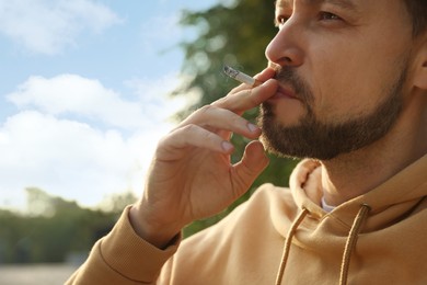 Photo of Handsome mature man smoking cigarette outdoors, closeup