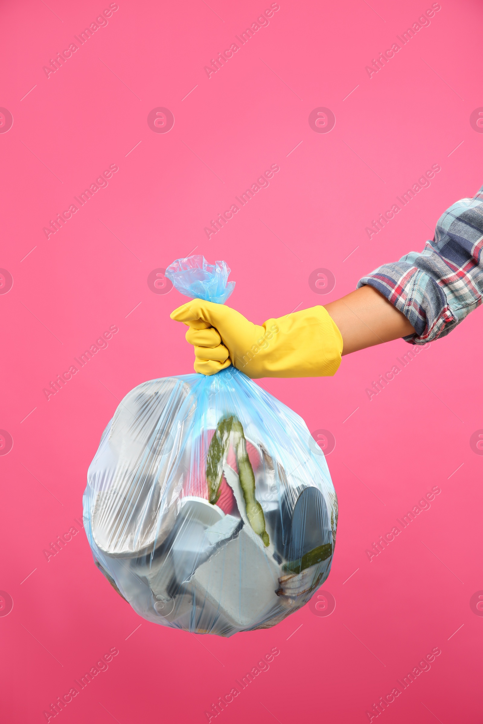 Photo of Woman holding full garbage bag on pink background, closeup