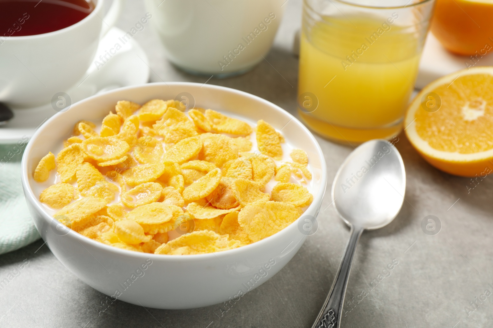 Photo of Tasty corn flakes with milk on light grey table