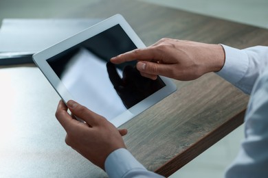 Photo of Man using tablet at wooden table, closeup