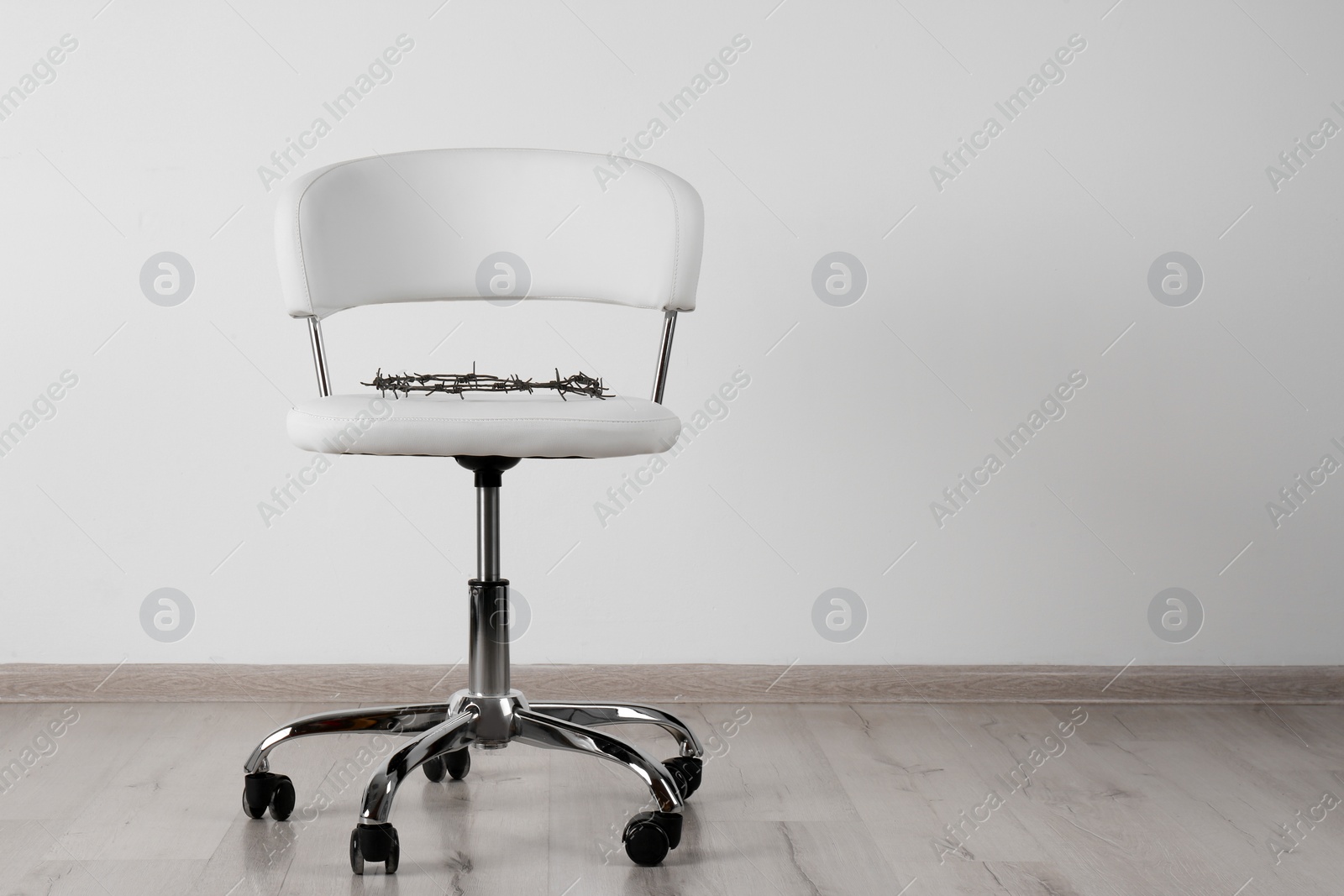 Photo of Chair with barbed wire near white wall, space for text. Hemorrhoids concept