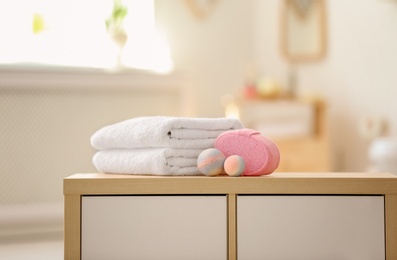 Photo of Clean towels and toiletries on table against blurred background