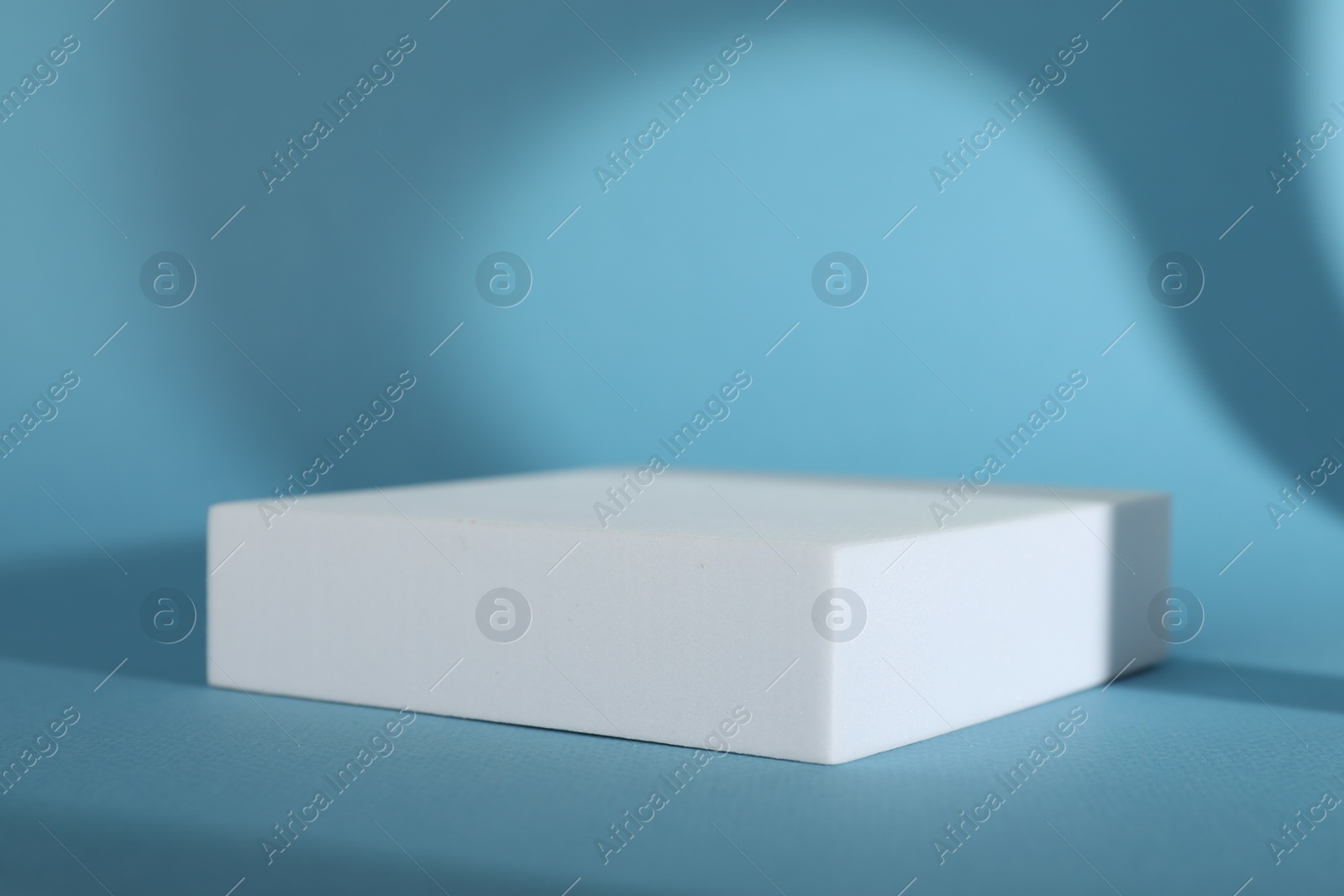 Photo of Presentation of product. Podium and shadows on light blue background. Space for text