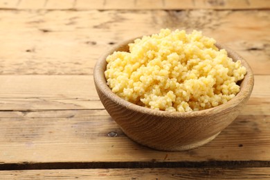 Photo of Tasty millet porridge in bowl on wooden table, closeup. Space for text