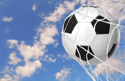 Soccer ball in net against blue sky