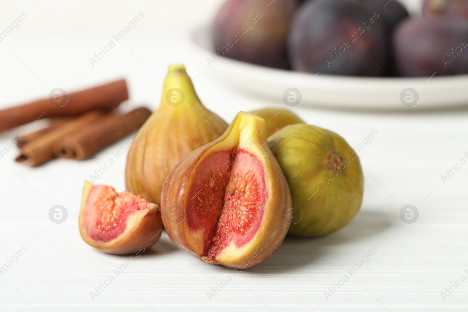 Photo of Tasty raw cut and whole figs on white table, closeup