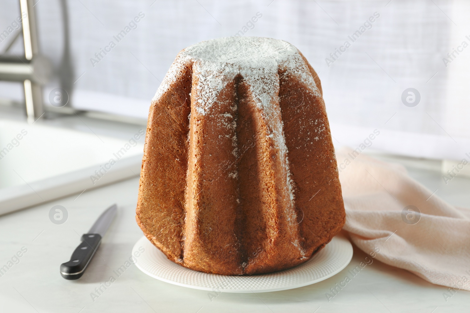 Photo of Delicious Pandoro cake decorated with powdered sugar on countertop. Traditional Italian pastry