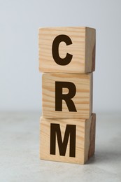 Photo of Abbreviation CRM of wooden cubes on light table, closeup. Customer Relationship Management