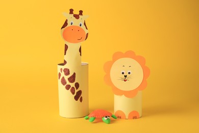 Photo of Toy giraffe and lion made from toilet paper hubs with plasticine turtle on yellow background. Children's handmade ideas