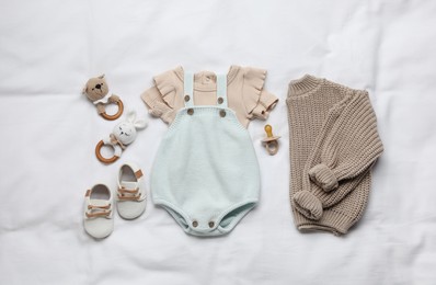 Photo of Layout with baby outfit and cute accessories on white bed, top view
