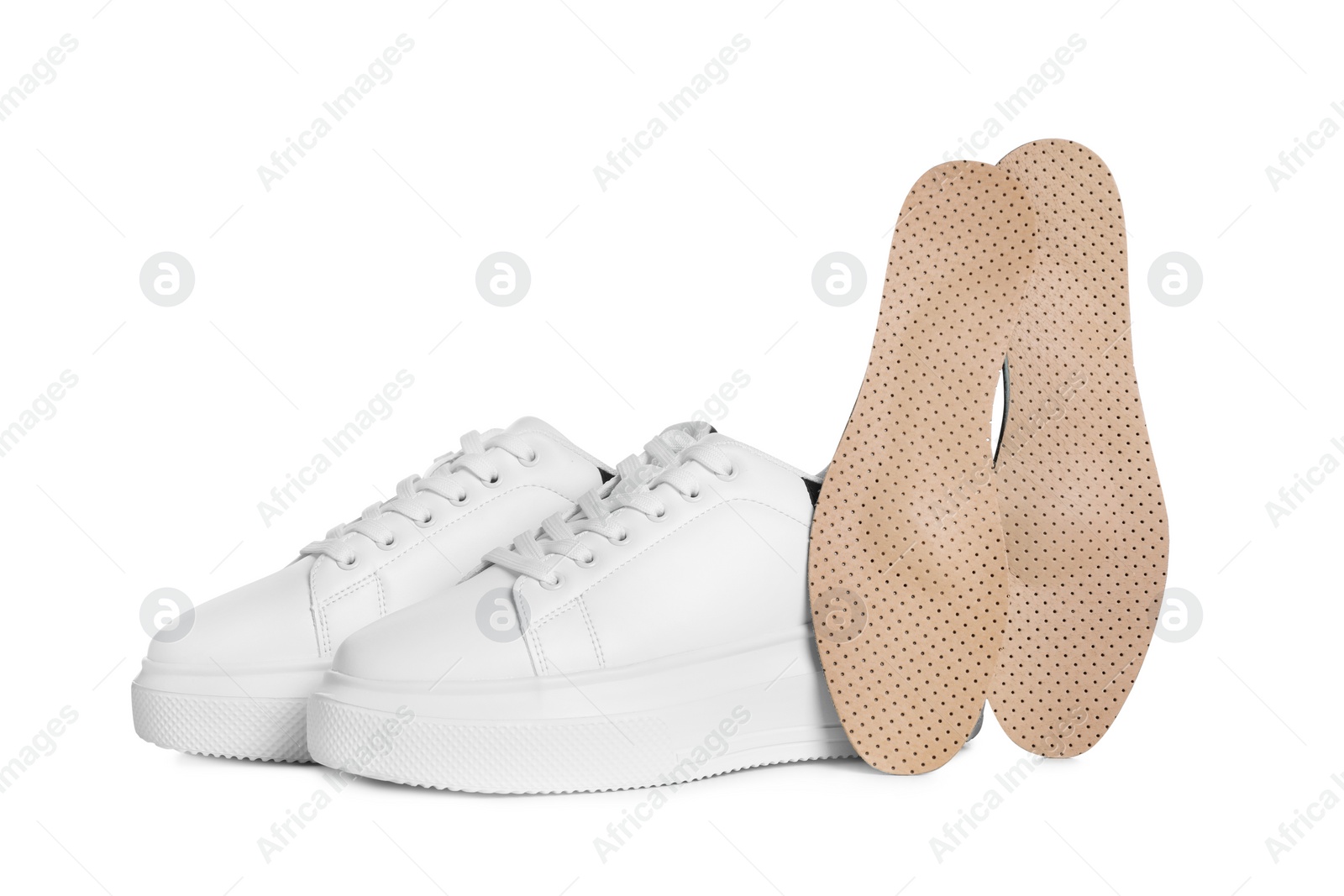 Photo of Orthopedic insoles near shoes on white background