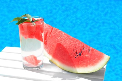 Photo of Refreshing drink in glass and sliced watermelon near swimming pool outdoors. Space for text