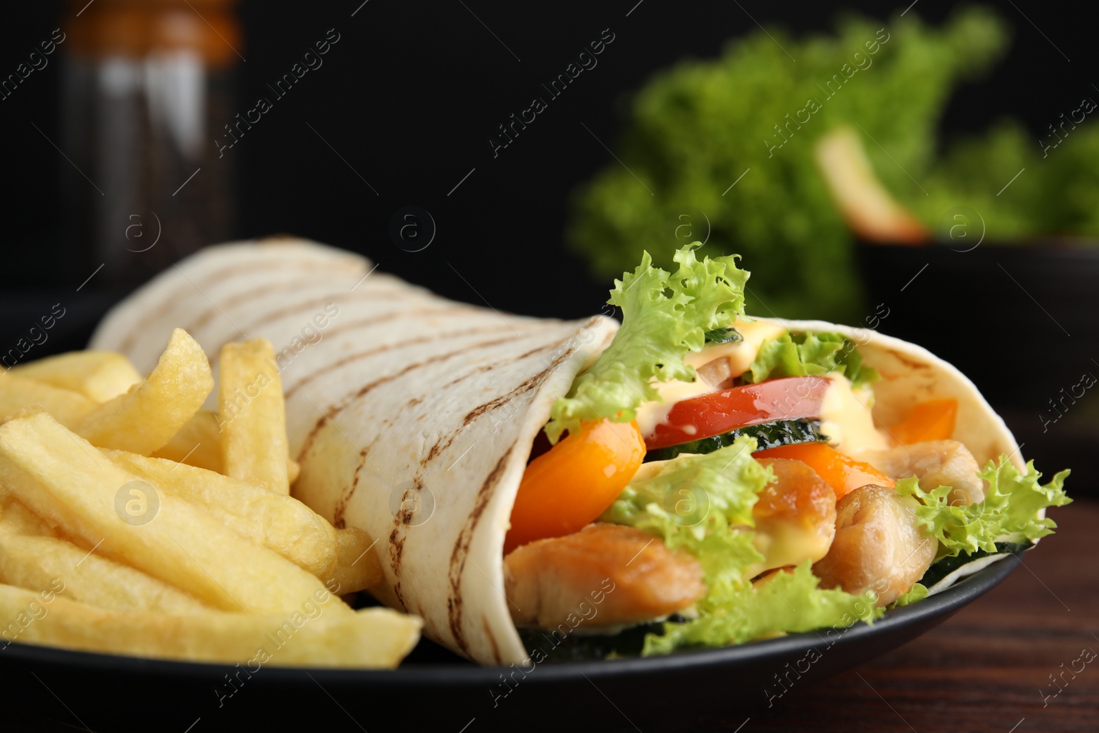 Photo of Delicious chicken shawarma and French fries on wooden table, closeup