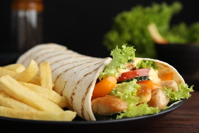 Photo of Delicious chicken shawarma and French fries on wooden table, closeup