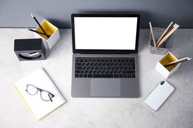 Photo of Modern workplace with laptop on table, top view. Blank screen for mockup