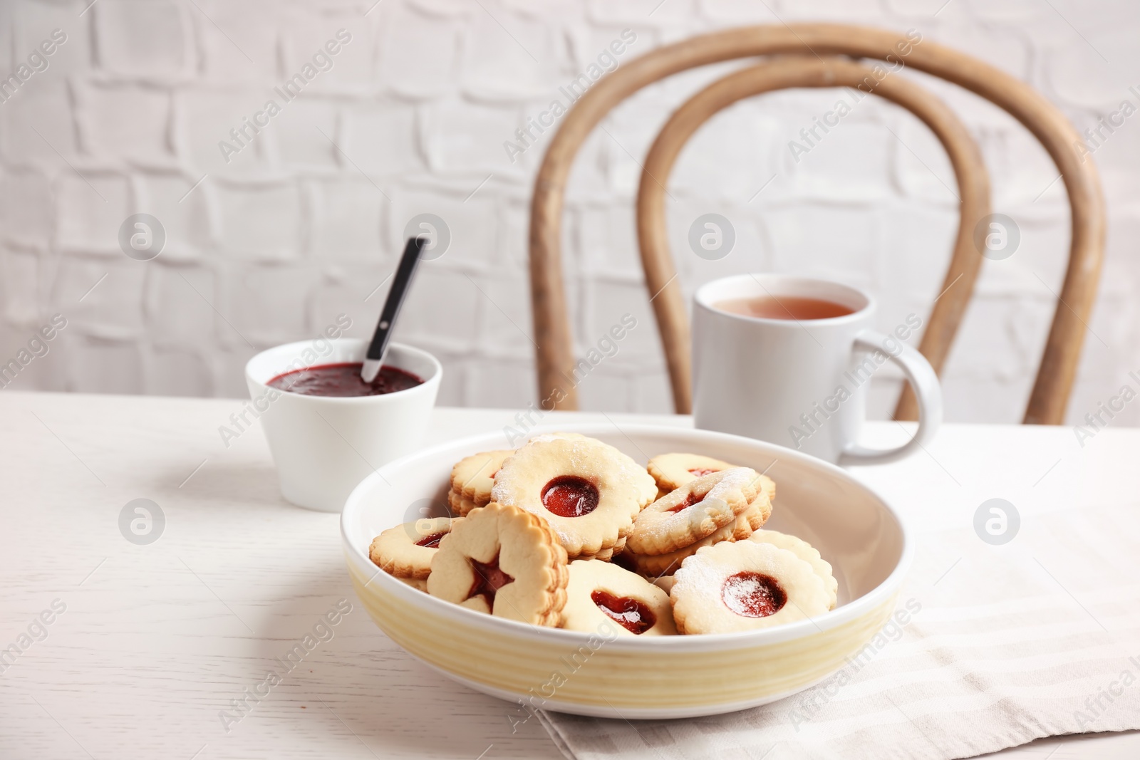 Photo of Traditional Christmas Linzer cookies with sweet jam and cup of tea on table