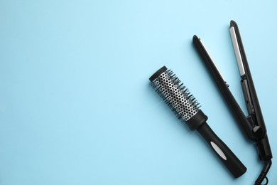 Photo of Hair straightener and round brush on light blue background, flat lay. Space for text
