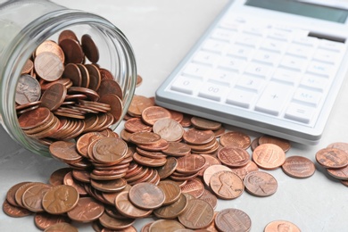 Photo of Overturned glass jar with coins and calculator on table, closeup