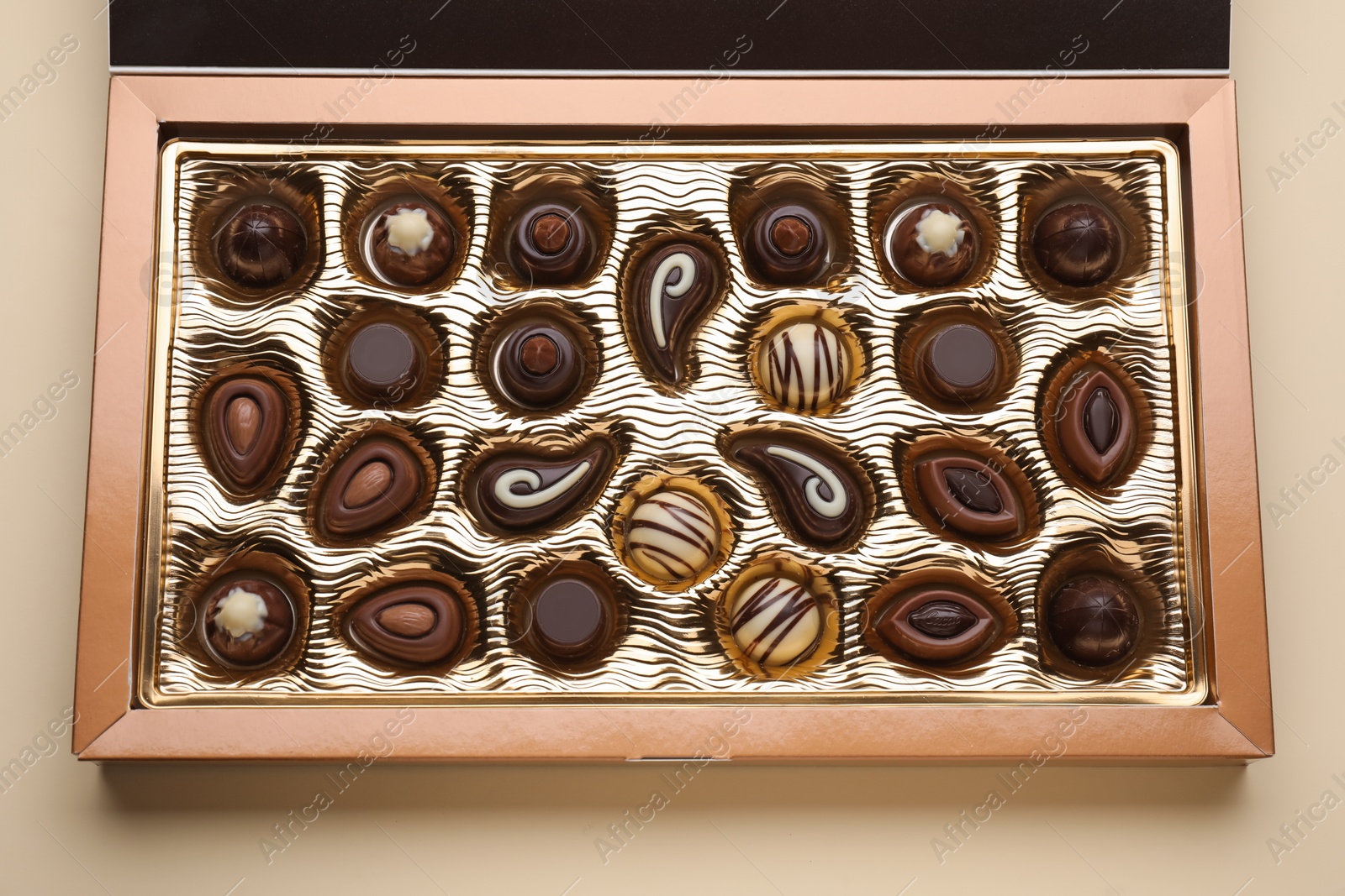 Photo of Box of delicious chocolate candies on beige background, top view