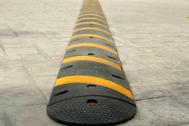 Photo of Striped plastic speed bump on pavement outdoors, closeup