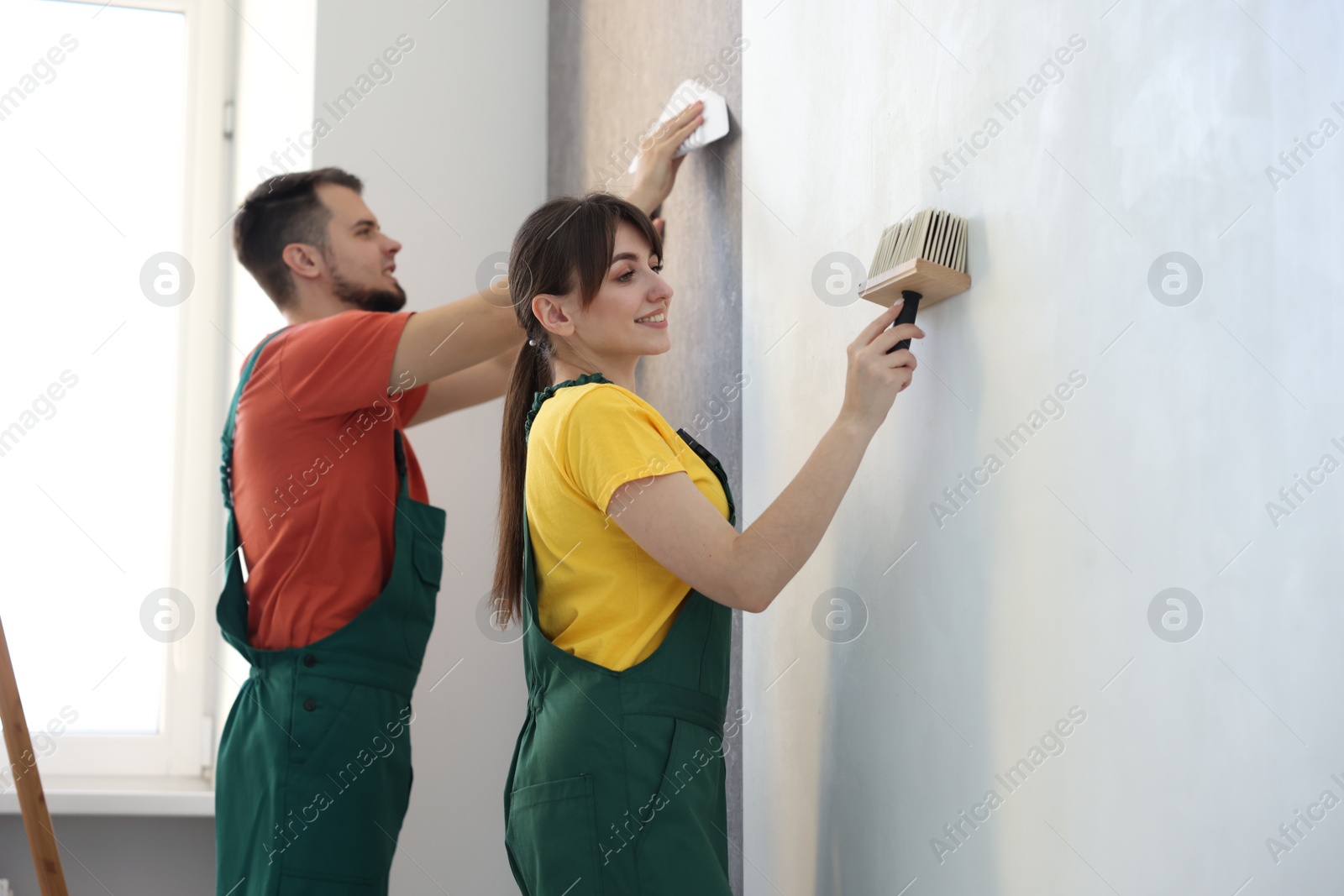 Photo of Workers hanging stylish gray wallpaper in room