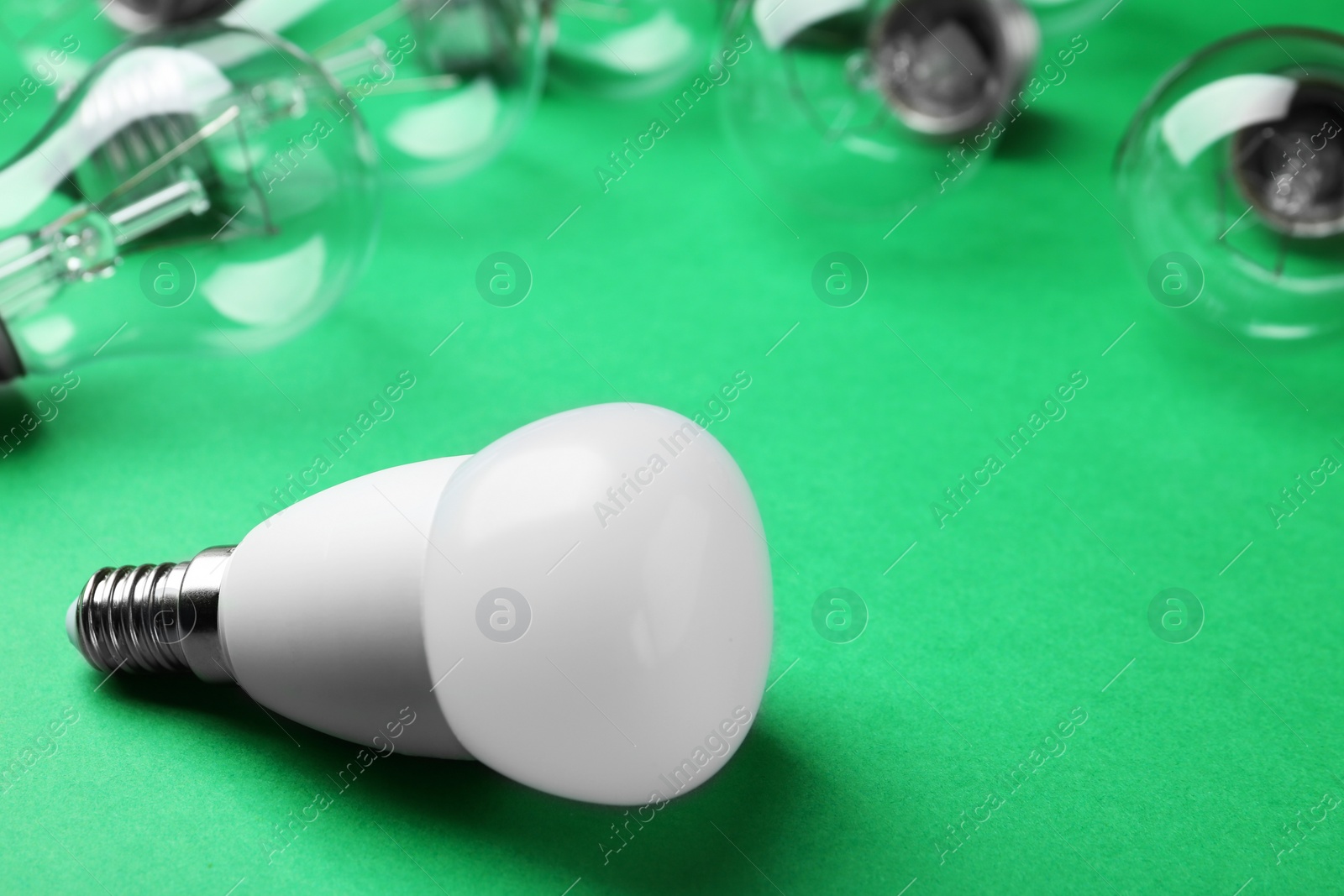 Photo of LED and incandescent lamp bulbs on green background, space for text